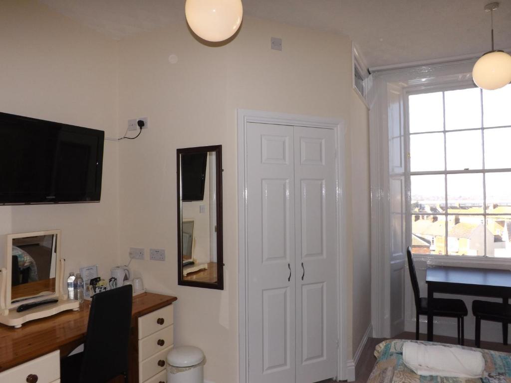 a room with a white door and a desk with a mirror at The Edenhurst Guesthouse in Weymouth