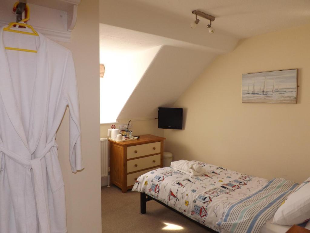 a bedroom with a bed and a robe hanging on a wall at The Edenhurst Guesthouse in Weymouth