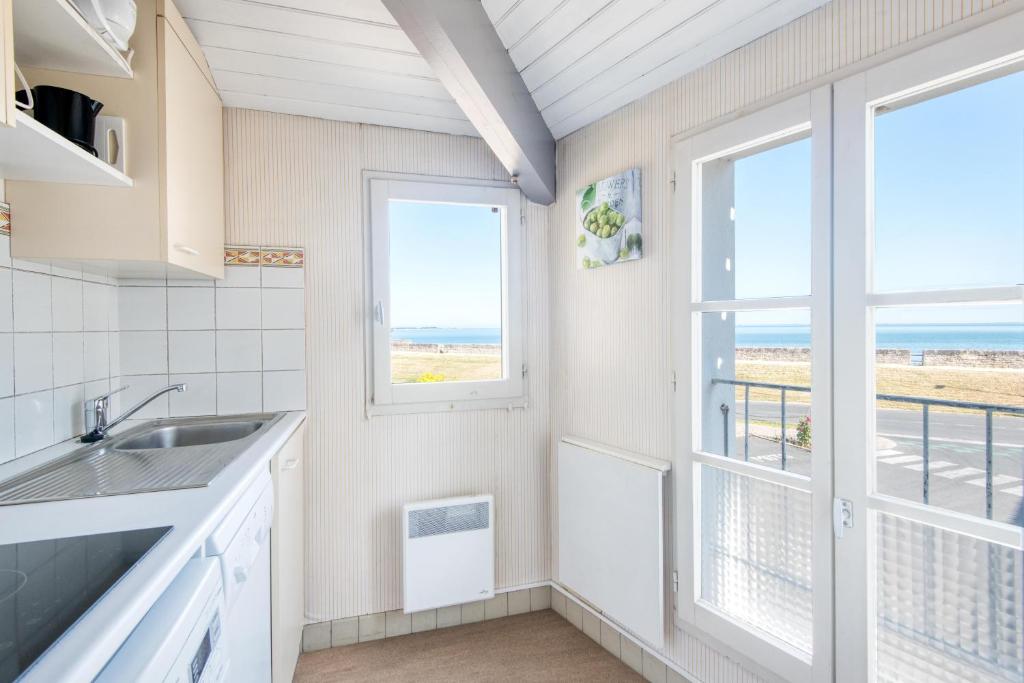 d'une cuisine avec évier et d'une fenêtre avec vue sur la plage. dans l'établissement Appartement Ombrine, à Saint-Martin-de-Ré