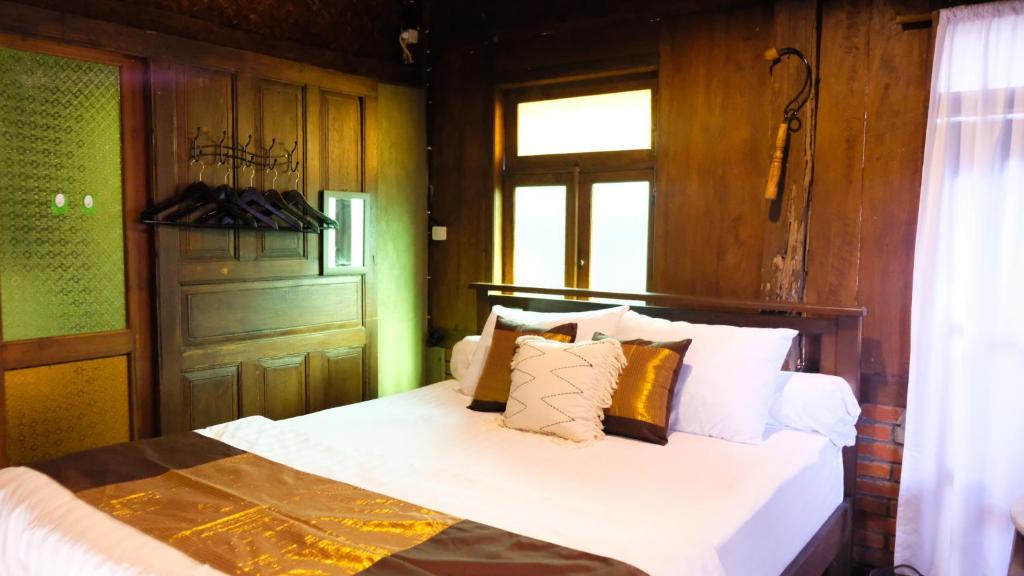 Un dormitorio con una cama con sábanas y almohadas blancas. en Jogja ethnic house, en Yogyakarta