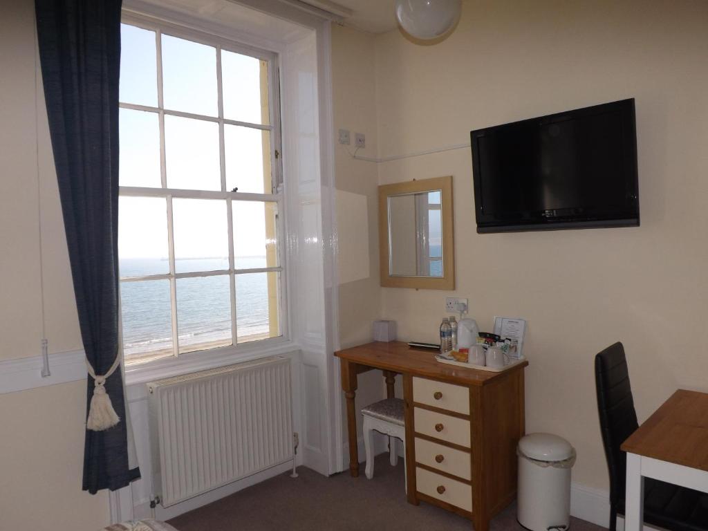 a room with a desk and a television and a window at The Edenhurst Guesthouse in Weymouth