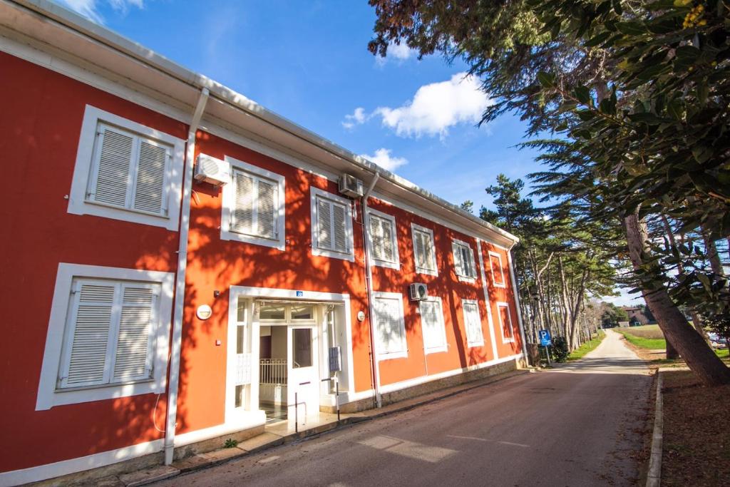 un bâtiment orange et blanc sur le côté d'une rue dans l'établissement Apartments Valdepian, à Umag