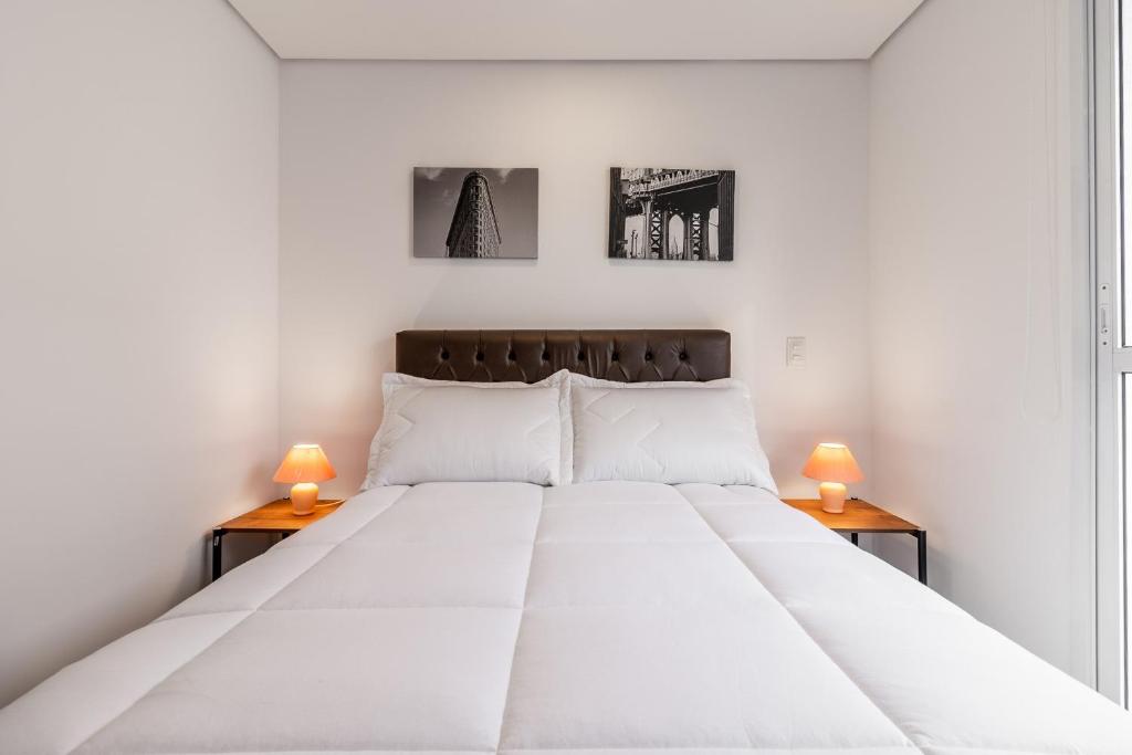 a bedroom with a large white bed with two lamps at Studio Bela Vista Teatro Renault in Sao Paulo