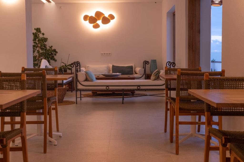 un ristorante con divano, tavoli e sedie di Hostal Aigua Clara a Playa Migjorn