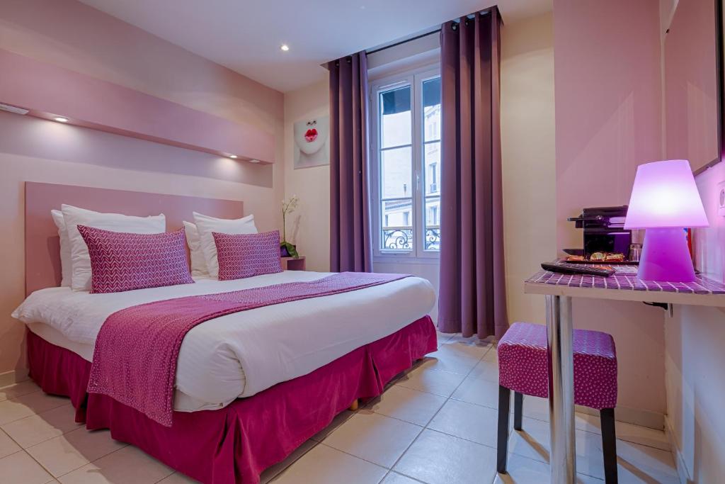 a bedroom with a bed and a table with a lamp at Pink Hotel in Paris