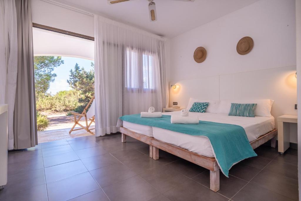 a bedroom with a large bed and a large window at Hostal Aigua Clara in Playa Migjorn