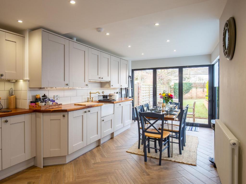a kitchen with white cabinets and a table with chairs at Trinity Cottage in Shottery