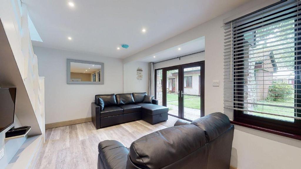 a living room with a leather couch and a large window at 48 Trevithick Court, Tolroy Manor in Hayle
