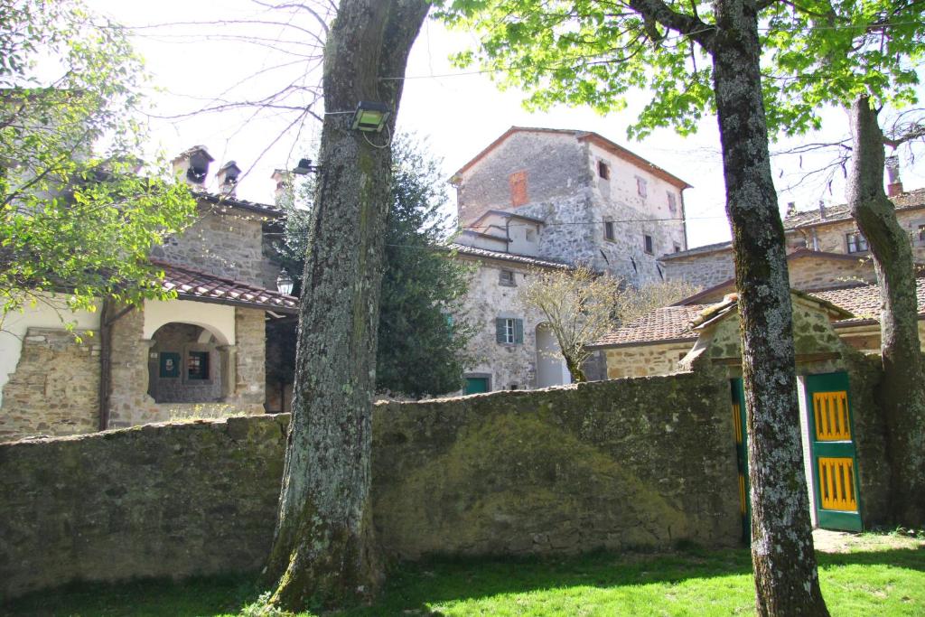 an old house behind a stone wall with trees at Castello di Sarna in Chiusi della Verna