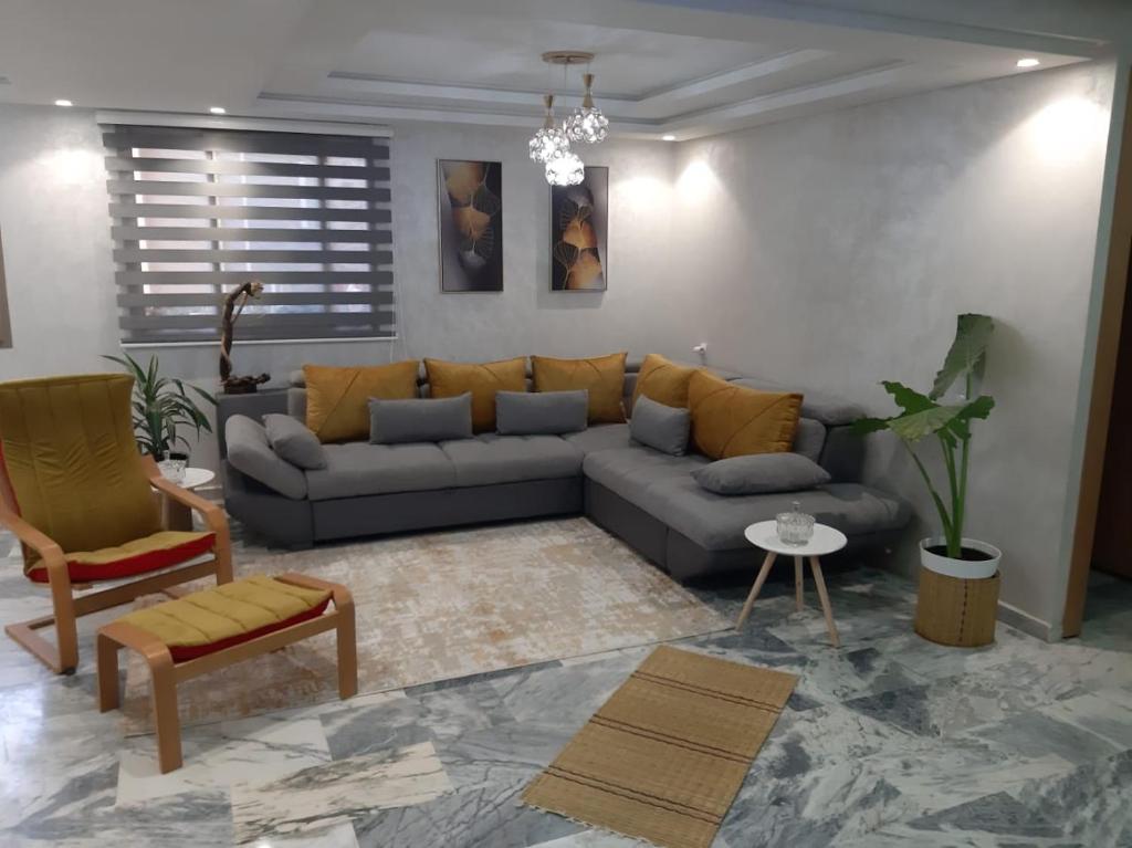 a living room with a gray couch and yellow pillows at Welcome to Rabat Technopolis, Sala jadida, the book is open, We propose a private suite in a shared apartment, Dears A rab couples you may need a marriage certificate to rent the room According to Moroccan law, Thank you in advance in Oulad Yakoub