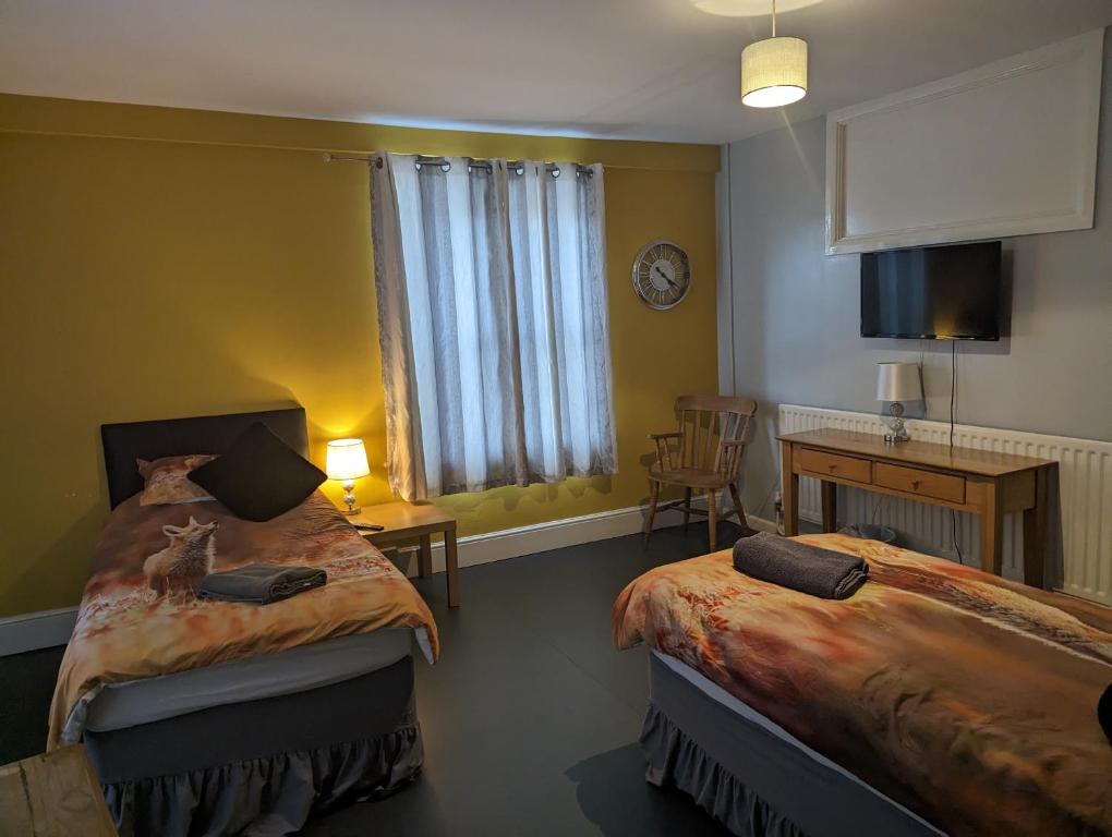 a bedroom with two beds and a desk and a window at The Fox in Bristol