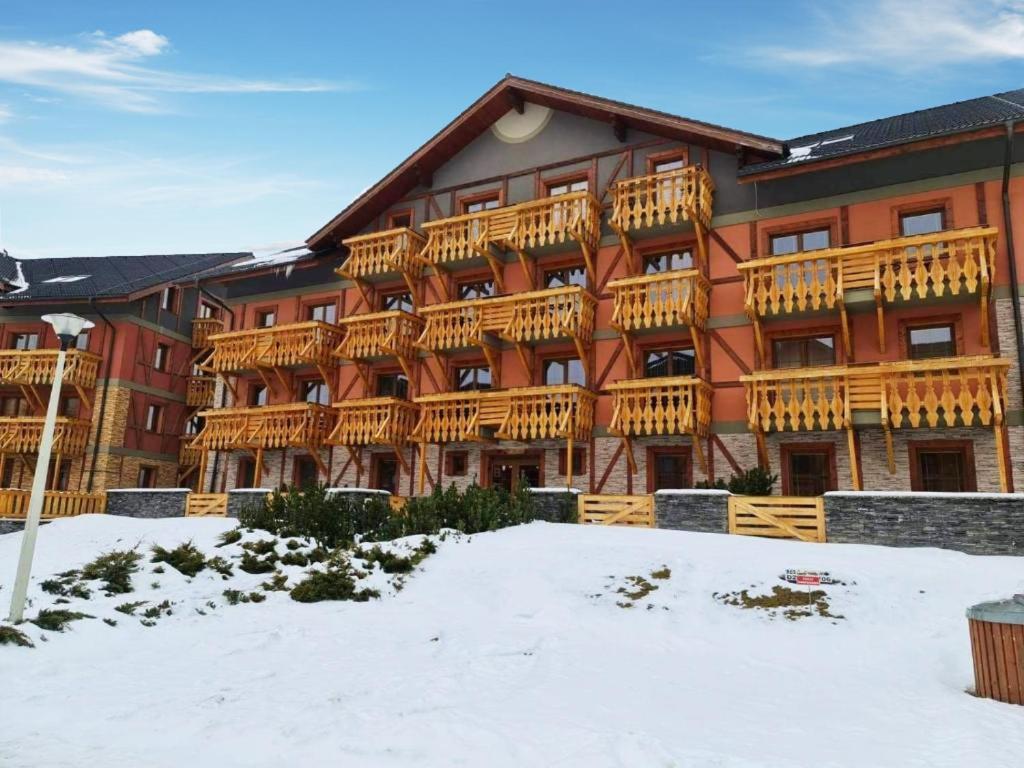 a large building with wooden balconies in the snow at Comfortable One-Bedroom Apartment TATRAGOLF in Veľká Lomnica