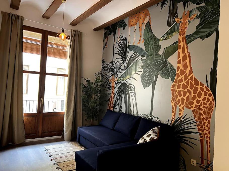 a living room with a blue couch and a mural of giraffes at El negrito, apartamento centro in Valencia