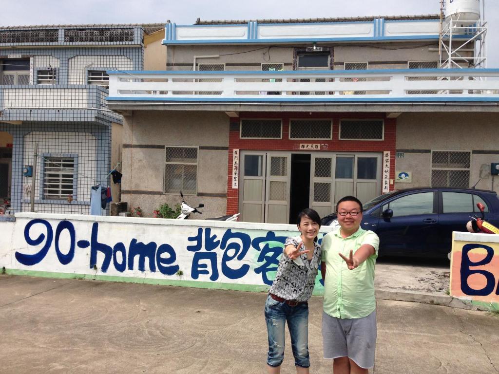 een man en een vrouw die voor een spandoek staan bij Go home backpackers in Huxi