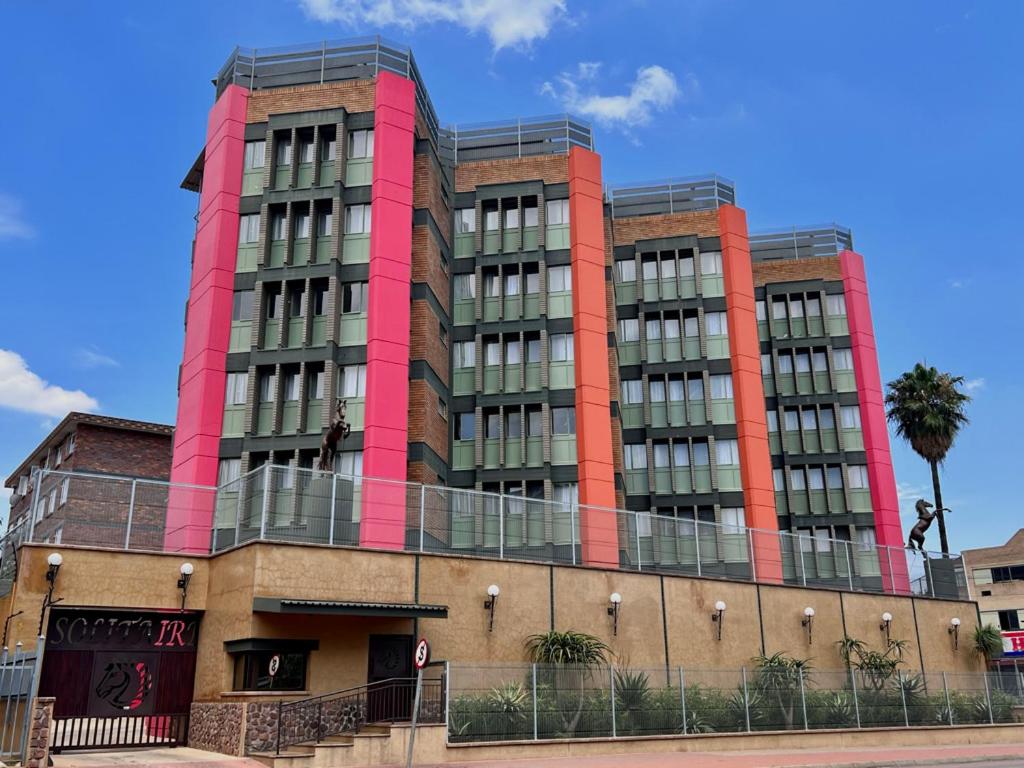 a tall red building with a palm tree in front of it at Solitaire Guest Apartments in Pretoria
