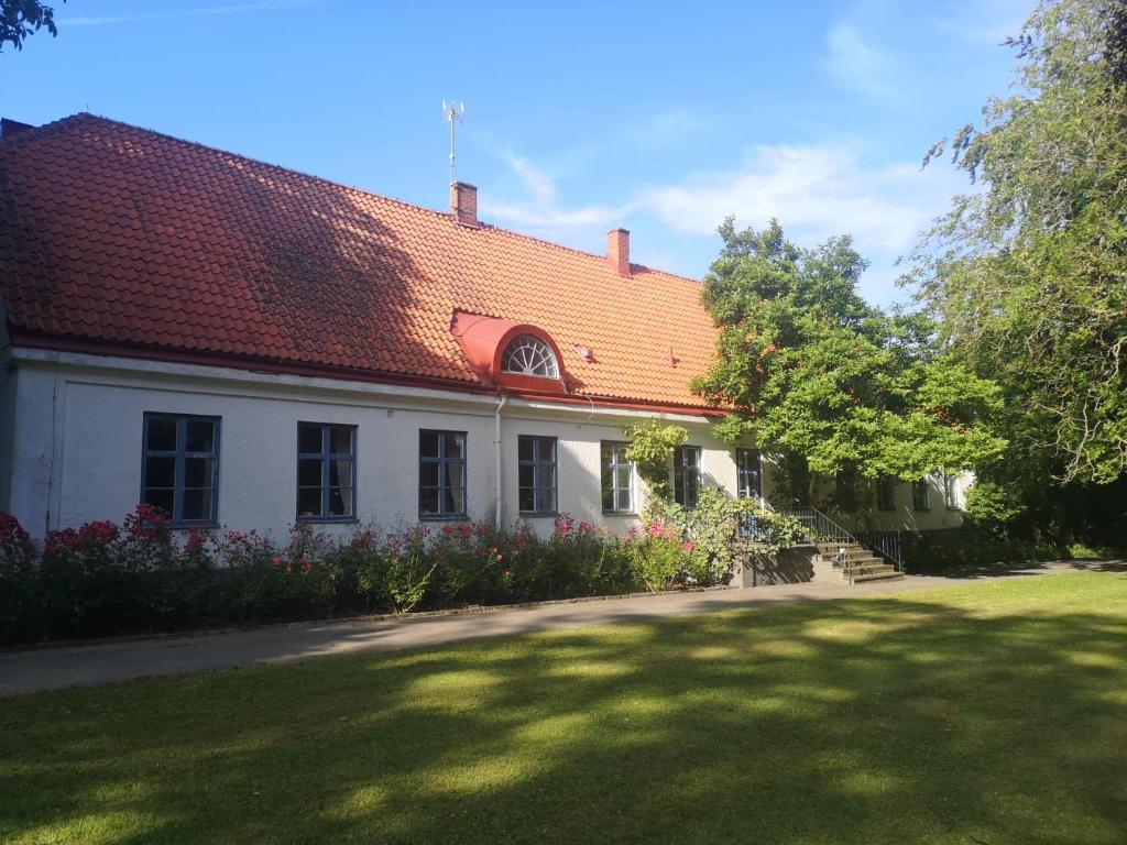 a white house with a red roof and a yard at Äspögården Bed & Breakfast in Klagstorp