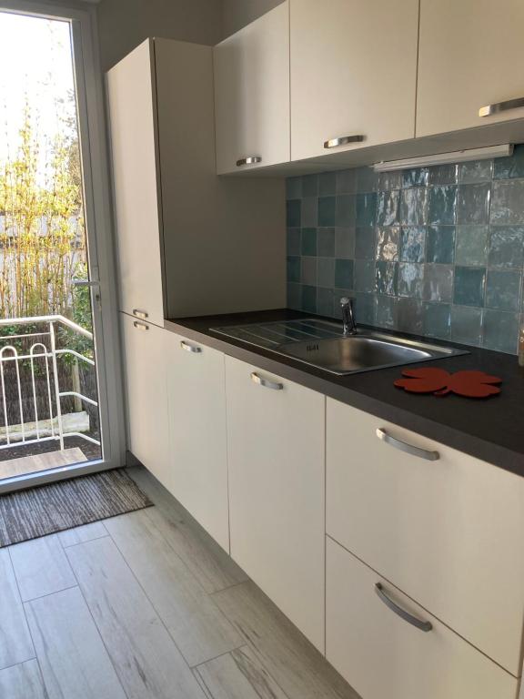 eine Küche mit weißen Schränken, einem Waschbecken und einem Fenster in der Unterkunft Villa sept fonds in Royan