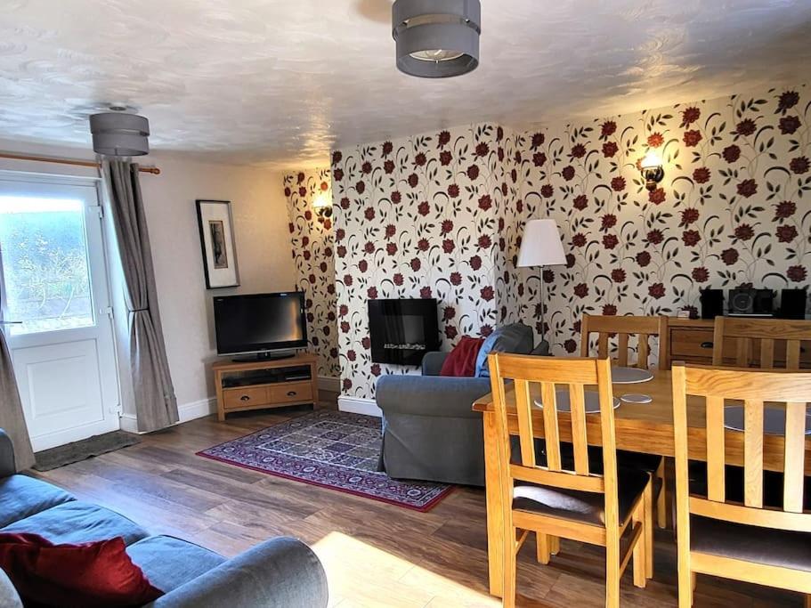 ein Wohnzimmer mit einem Tisch, einem Sofa und einem TV in der Unterkunft Pinfold Cottage on the edge of lake district in Bothel
