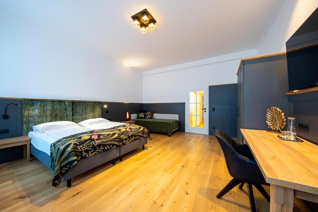 a bedroom with a bed and a desk and a table at Hotel Unter den Linden in Krems an der Donau