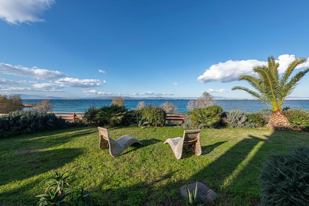 deux chaises assises dans l'herbe près de l'océan dans l'établissement Dream House, à Áyioi