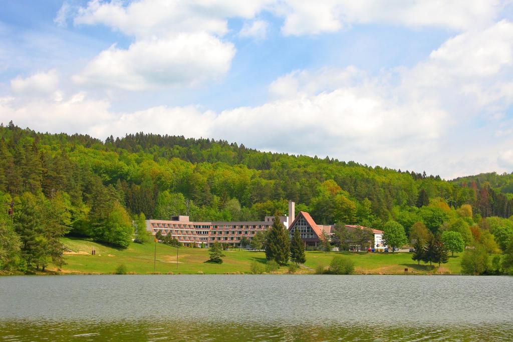 a large building on a hill next to a lake at Apartmán Všemina 300 in Všemina