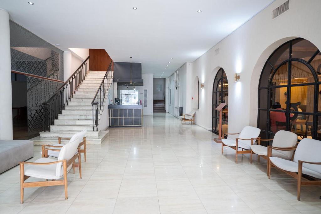 sala de estar con escalera y sillas blancas en Hotel Posada Del Sol en Salta