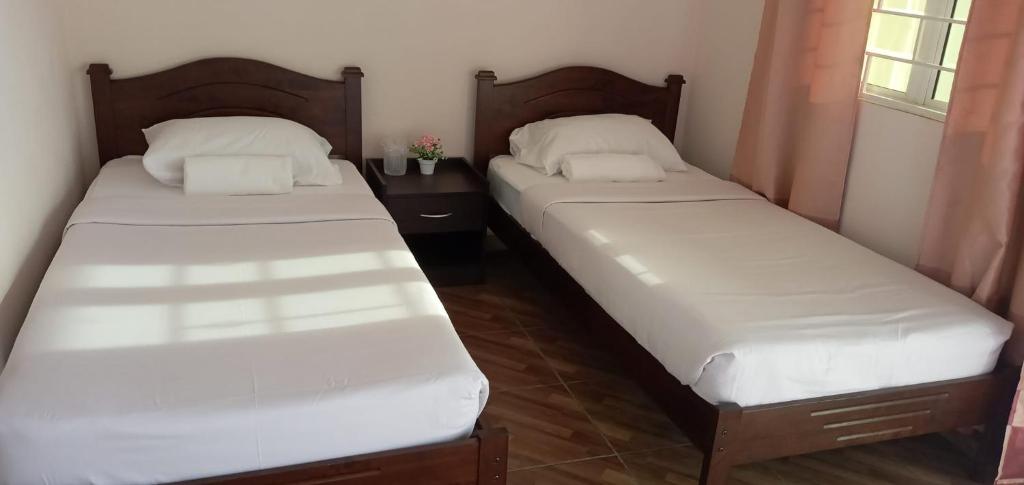 2 camas individuales en una habitación con ventana en Margereth Cottage, en Kuala Penyu