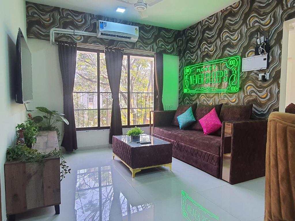 a living room with a couch and a sign on the wall at OSI Apartments Khar West in Mumbai