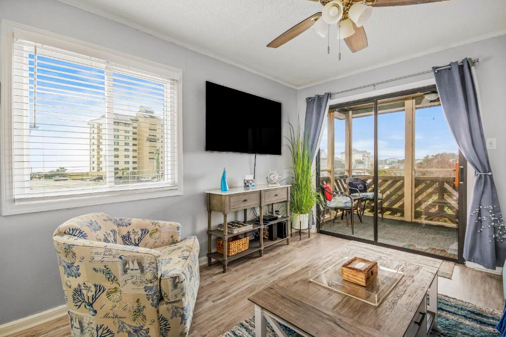 a living room with a tv and a chair and a table at Waipani A-18 in Myrtle Beach