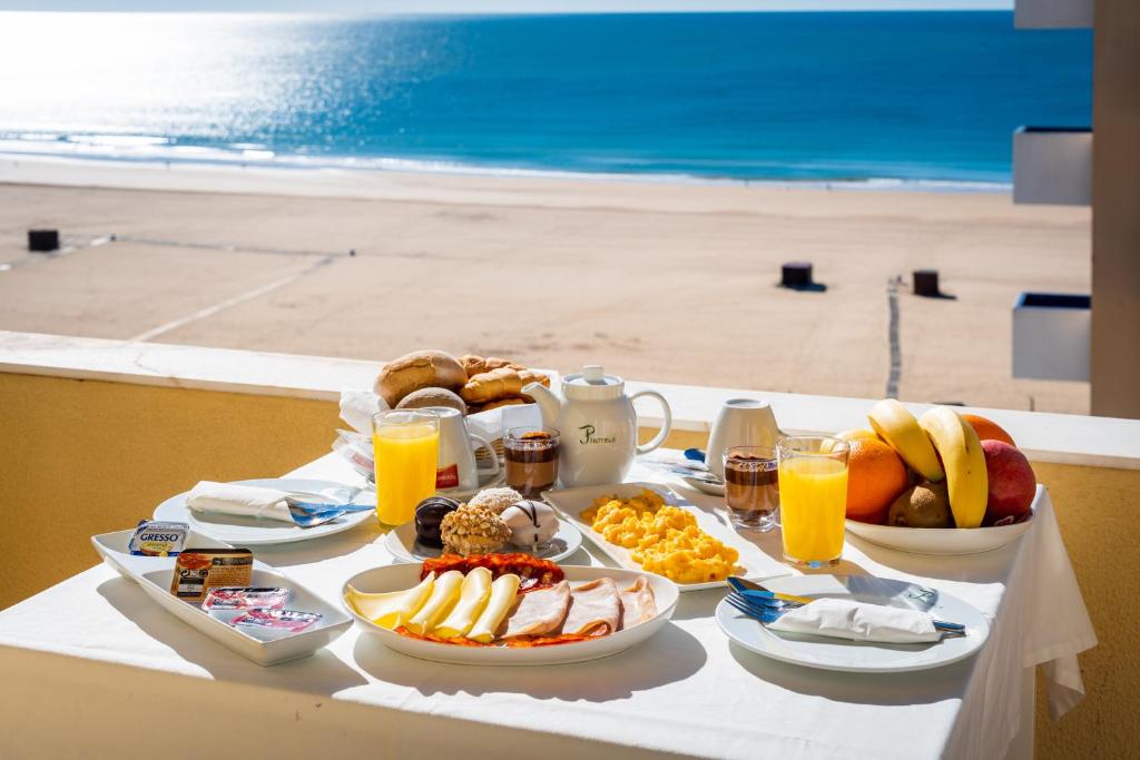 een tafel met ontbijtproducten en drankjes op het strand bij Hotel Santa Catarina Algarve in Portimão