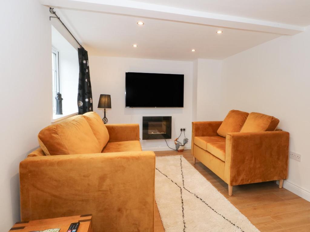 a living room with two chairs and a flat screen tv at Butterfly Cottage in Rossendale