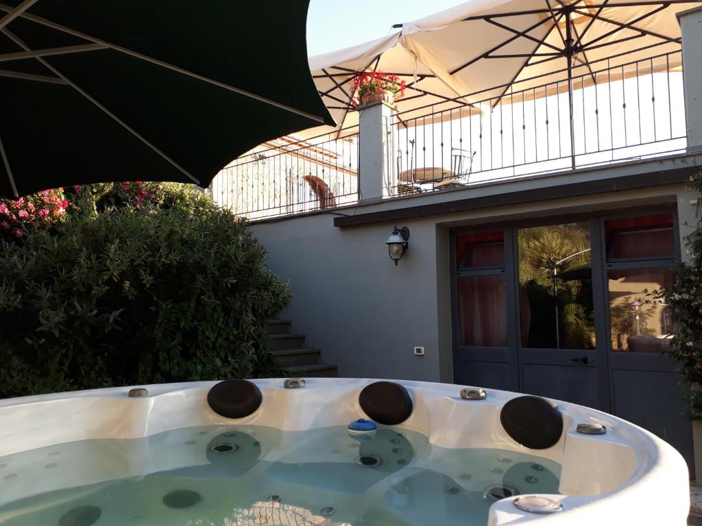 a hot tub in front of a house with an umbrella at Arpaderba B&B in Livorno