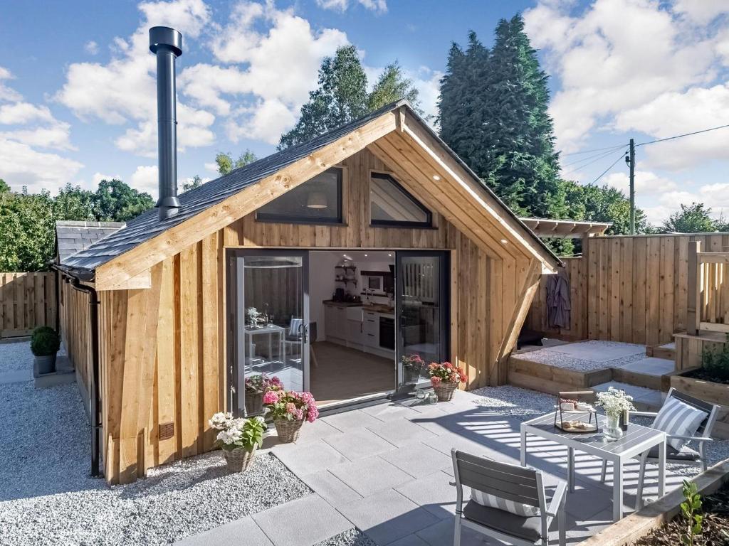 a wooden shed with a patio and a table at Olchard Lodge in Ideford