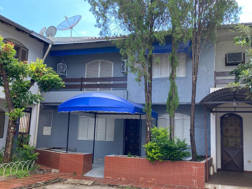 ein blaues Haus mit einem blauen Schirm davor in der Unterkunft Ampla Casa em condomínio in Foz do Iguaçu