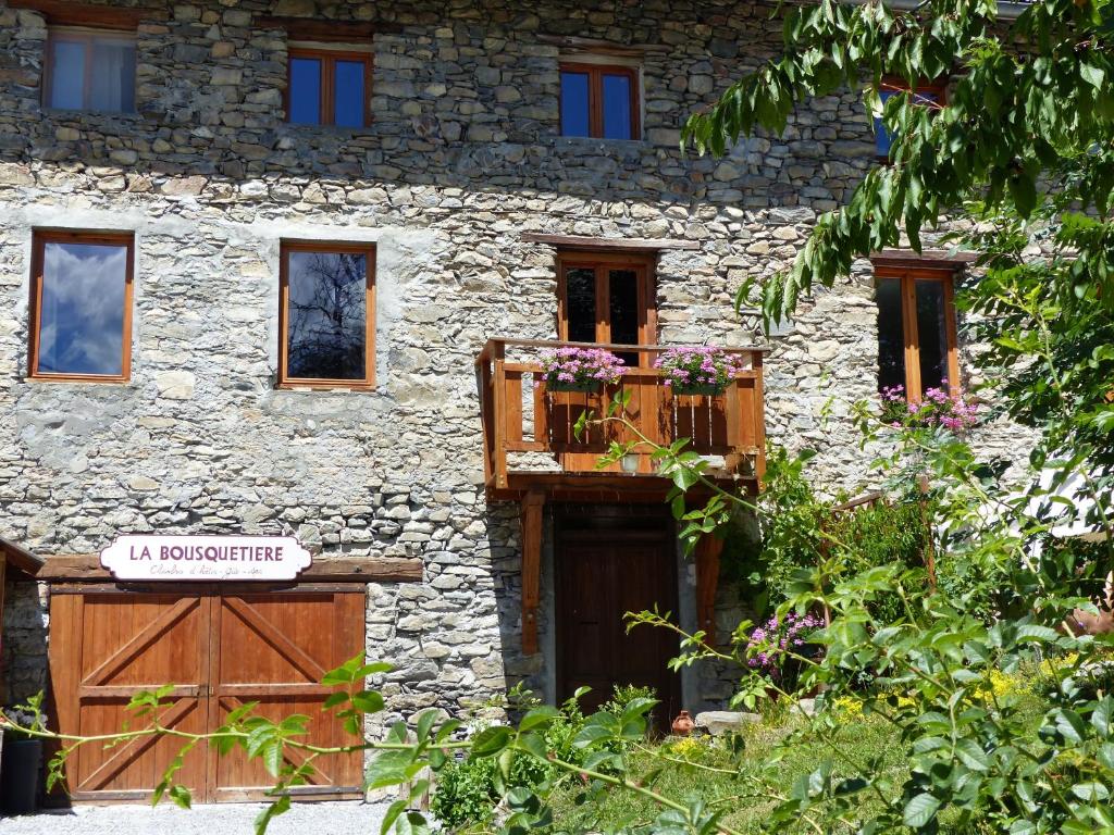 un edificio de piedra con puerta de madera y balcón en La Bousquetière, en Jausiers