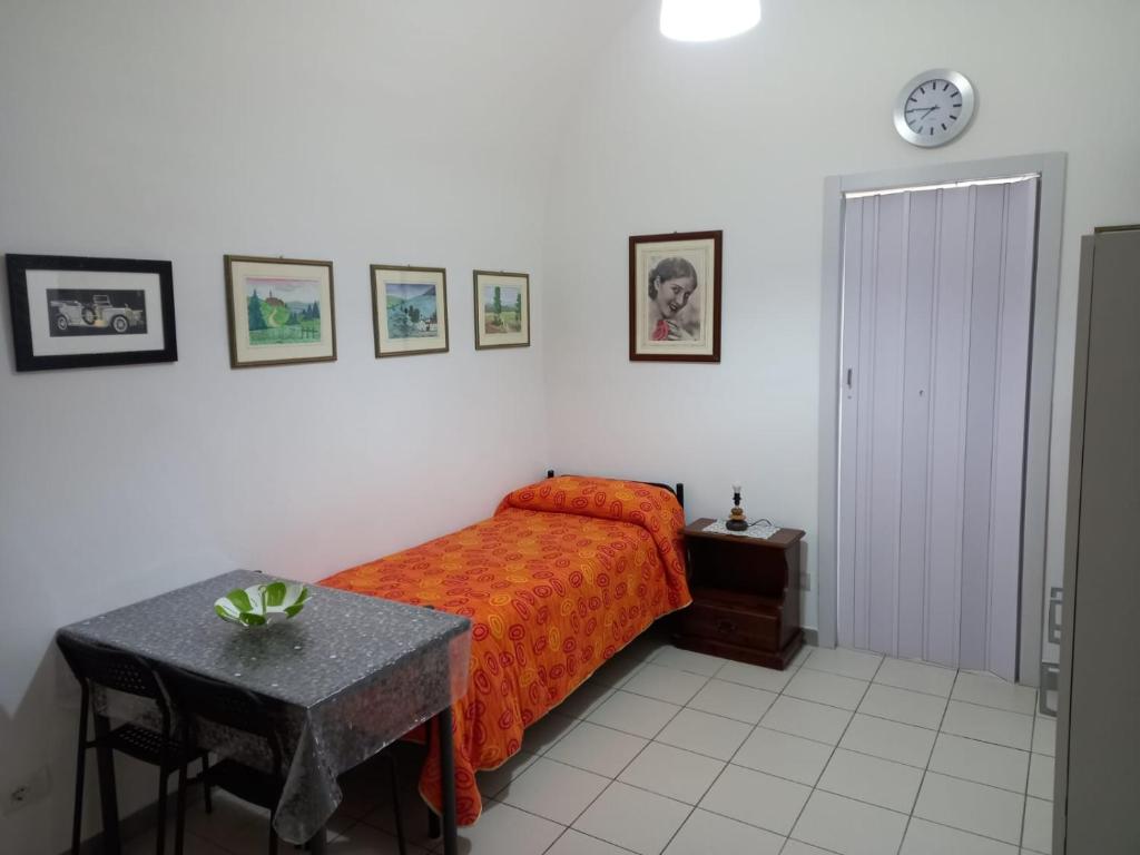 a bedroom with a bed and a table and pictures on the wall at MINI HOUSE in Montescaglioso
