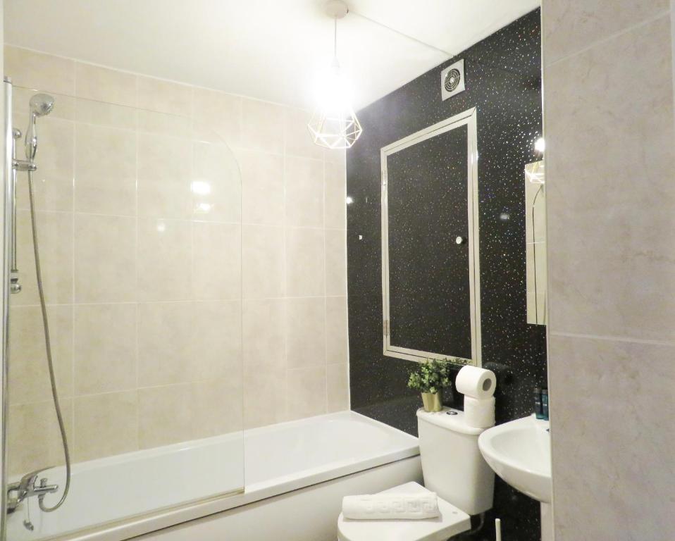 a bathroom with a tub and a toilet and a sink at Tudors eSuites Five Ways Private Terrace & Parking in Birmingham