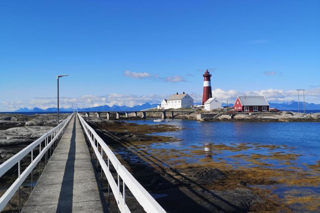 a wooden bridge with a lighthouse on a body of water at Tranøy Fyr in Tranøy