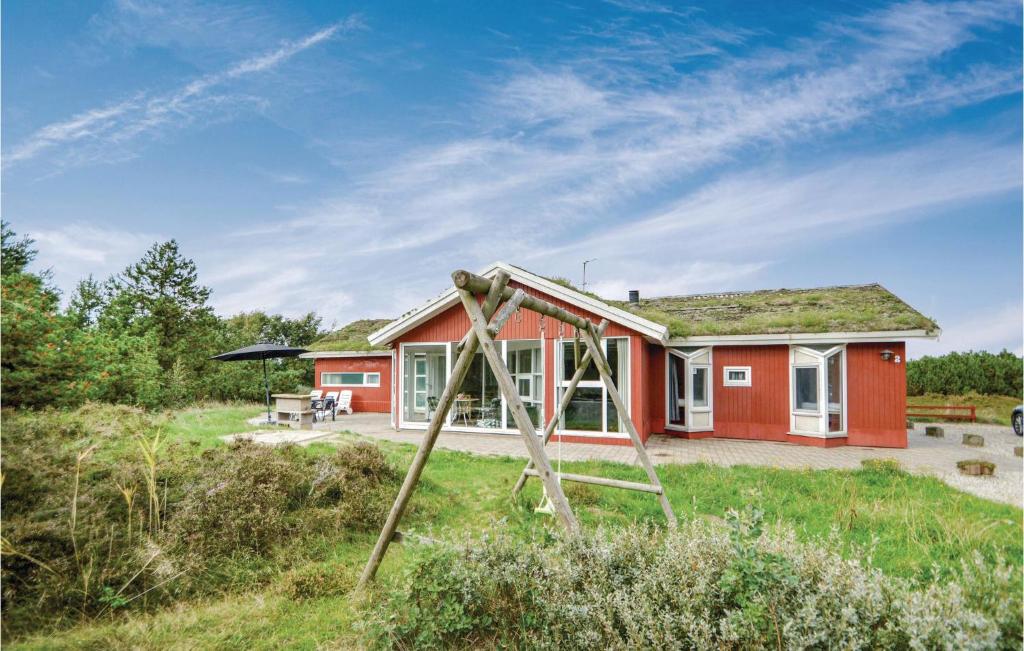 a red house with a yard with a swing at Stunning Home In Rm With Sauna in Bolilmark