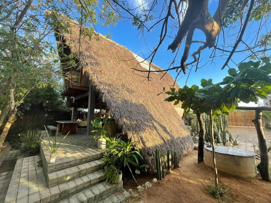 a thatch roofed house with stairs and a porch at Peaceful beachside artist-designed in Puerto Escondido