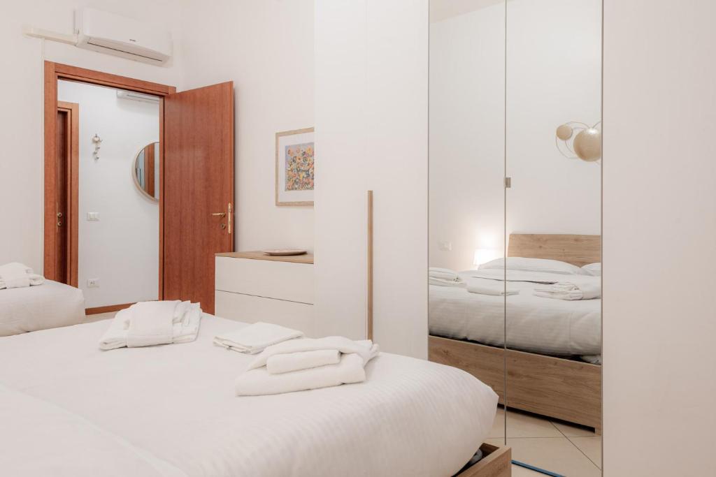 a white bedroom with two beds and a mirror at BnButler - Pellegrino Rossi, 42 - Ampio e Comodo per 5 in Milan