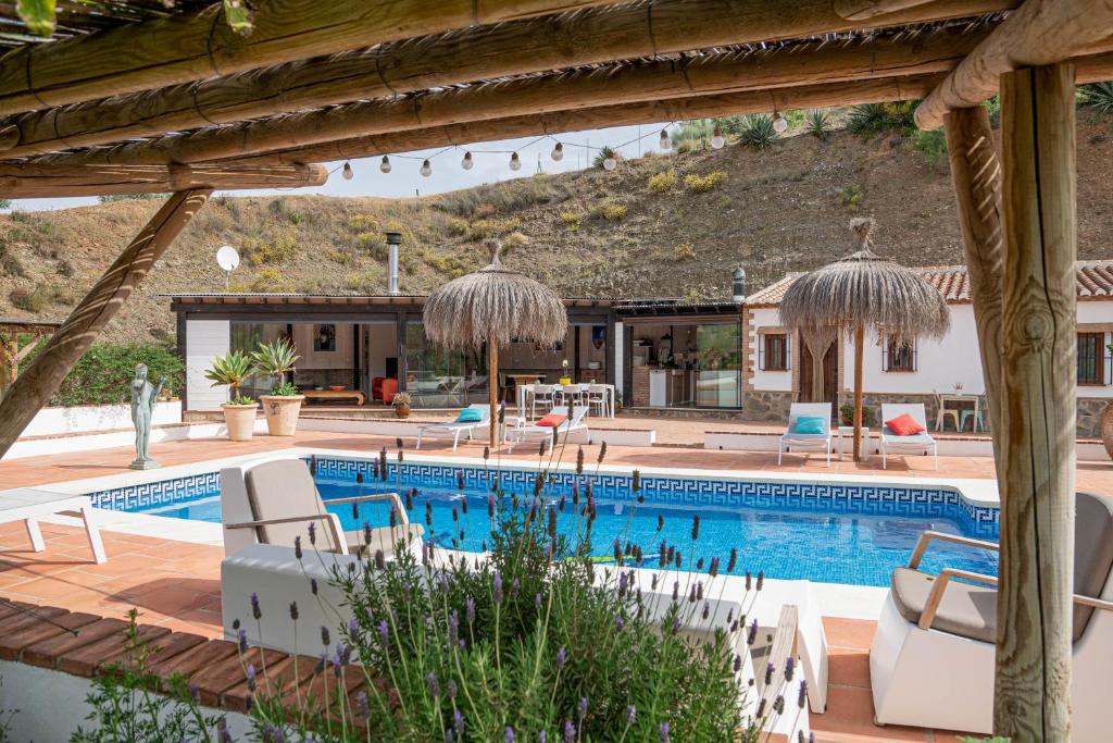 uma piscina com cadeiras e um resort em Finca Las Hierbas B&B em Álora