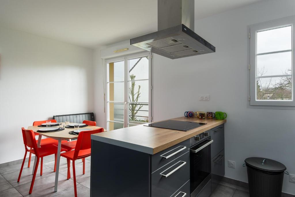 a kitchen with a counter and a table with red chairs at T2 Marvel Apartment Near DisneylandParis in Serris