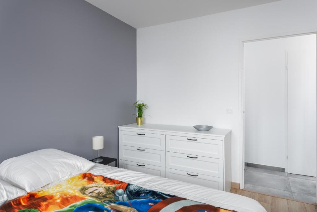 a white bedroom with a bed and a dresser at T2 Marvel Apartment Near DisneylandParis in Serris