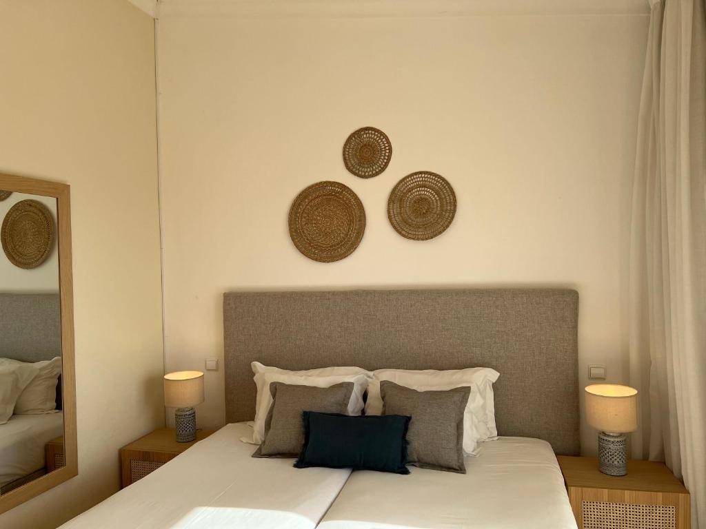 a bedroom with a bed with a mirror and two hats on the wall at Pestana Palm Gardens in Carvoeiro