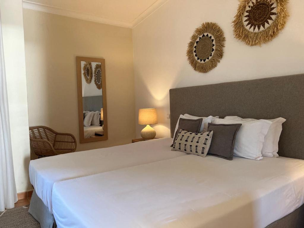 a bedroom with a large white bed with pillows at Pestana Palm Gardens in Carvoeiro