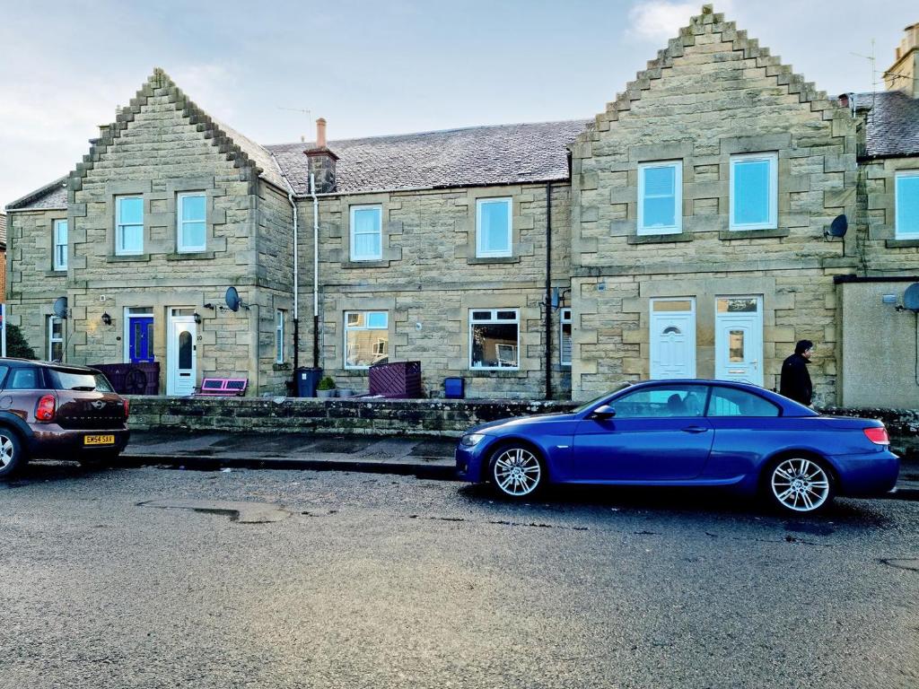 a blue car parked in front of a stone house at Cosy Penicuik Apartment in Penicuik