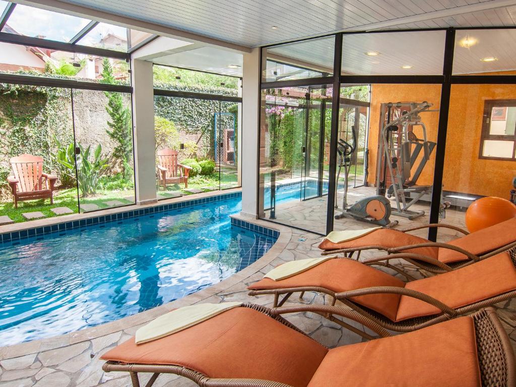 uma piscina com cadeiras laranja numa casa em Pousada Aguia Dourada em Monte Verde