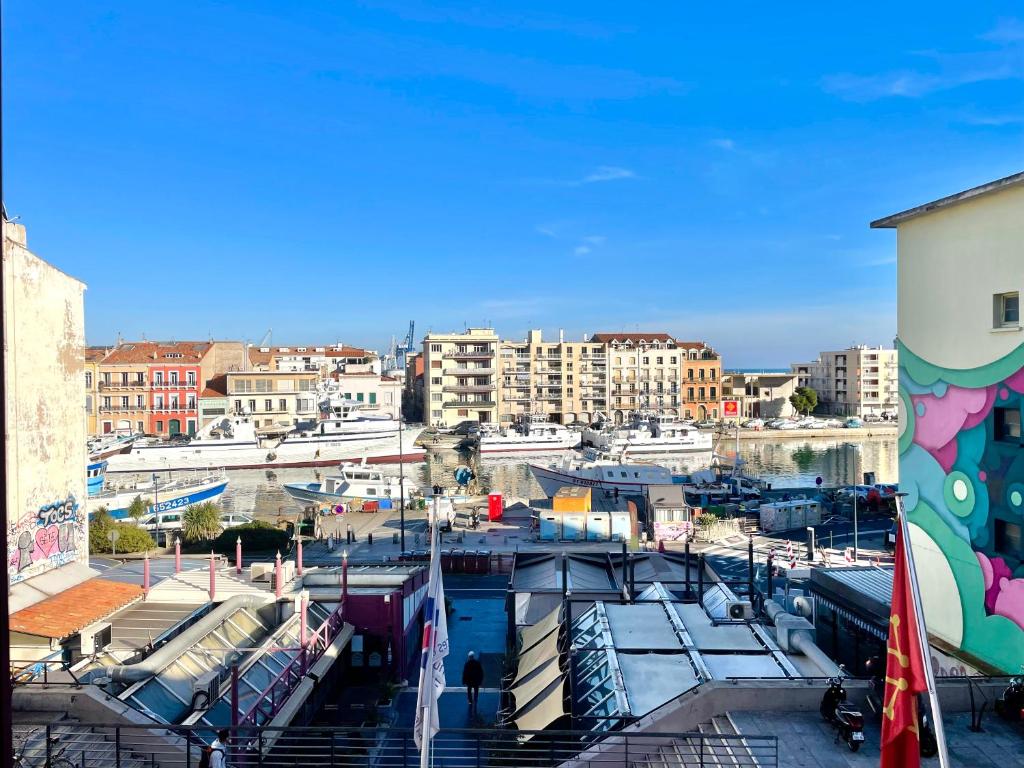 vistas a un puerto deportivo con barcos y edificios en Grand appartement avec vue sur quai en Sète