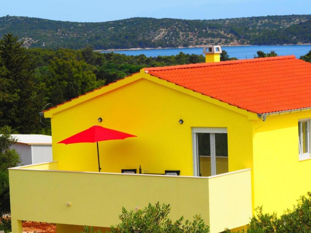 een geel huis met een rode paraplu erop bij Apartment Gaby in Božava